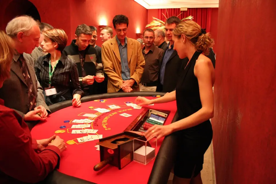 Une croupière distribue les cartes à une table de black-jack entourée d’invités