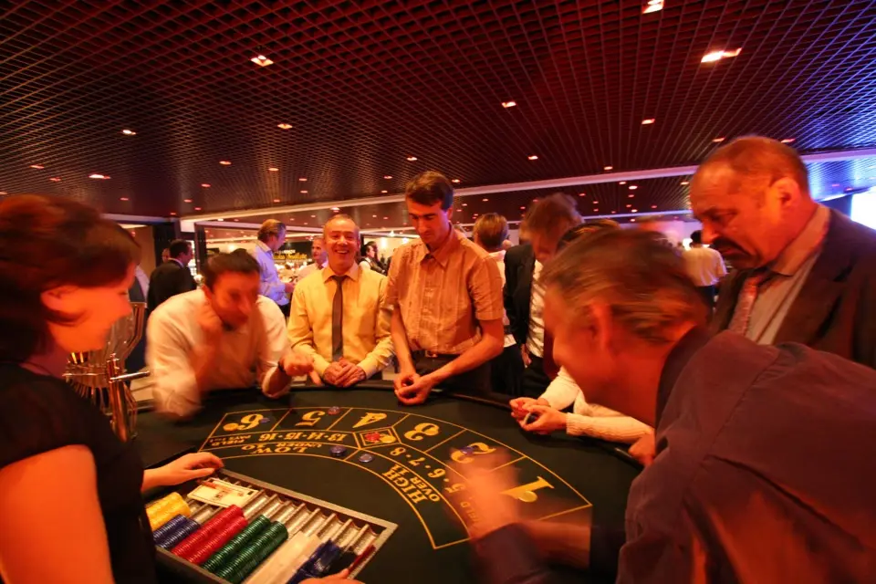 Des invités penchés sur une table de jeu, jetons en main, face à la croupière